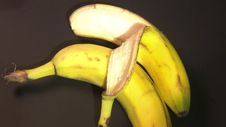 Zwei Bananen liegen nebeneinander, wobei es so wirkt, als würde eine Banane die andere umarmen.