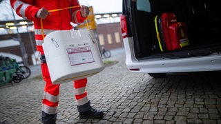 Ein Mitarbeiter des DRK stellt eine Kühlbox für eine Organspende in einen Transporter des Deutschen Roten Kreuzes.