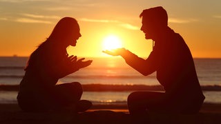 Silhouette eines verliebten Paares vor einem Sonnenuntergang (Symbolbild)