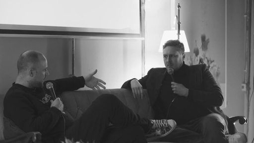 Die Podcast-Macher von Sucht & Süchtig Hagen Decker und John Cook sitzen auf einem Sofa vor Publikum und berichten von ihren Erfahrungen mit der Sucht.