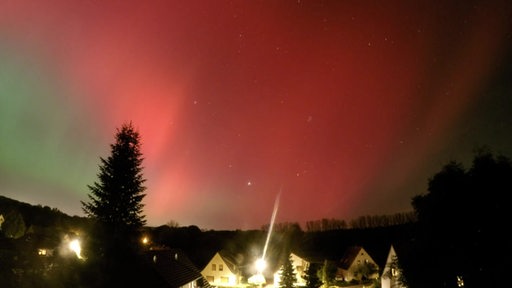 Über einigen Häusern sicht rote und grüne Polarlichter zu sehen