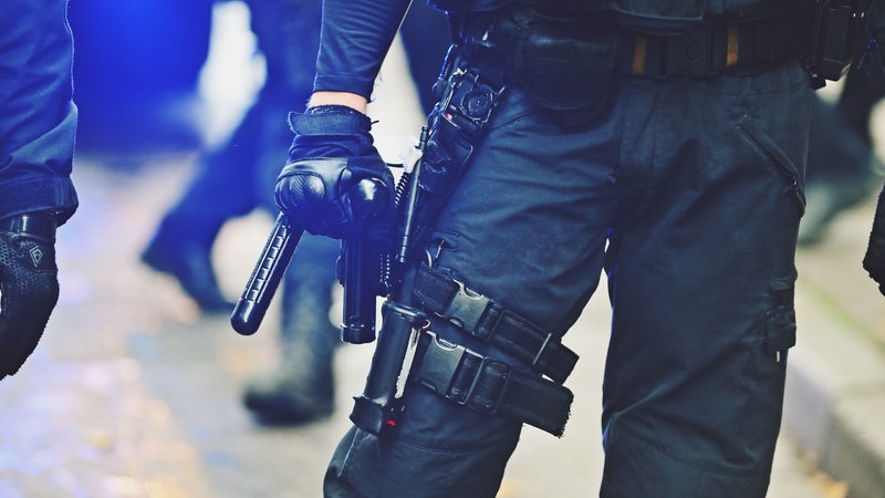 Ein Polizist hält einen Schlagstock in der Hand.