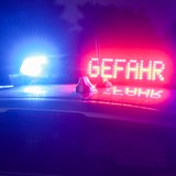 Mit Blaulicht und der Anzeige "Gefahr" steht ein Polizeifahrzeug auf der Autobahn.