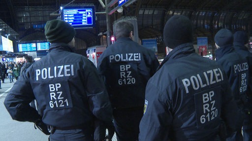 Polizisten stehen an einem Bahnhof auf einem Bahnsteig. 