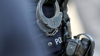 Handschellen am Einsatzgürtel eines Polizisten, darunter eine Schusswaffe