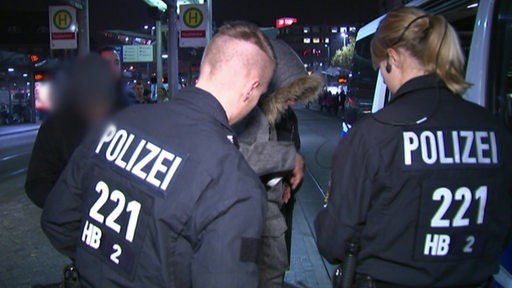 Zwei Polizeibeamte kontrollieren nachts eine Person am Bremer Hauptbahnhof