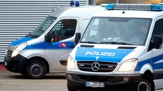 Zwei Polizeifahrzeuge vor einem Gebäude