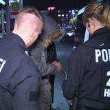 Zwei Polizisten bei einer Kontrolle an einer Haltestelle.