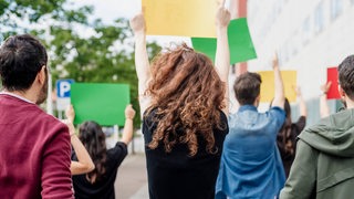 Menschen von hinten protestieren (Symbolbild)