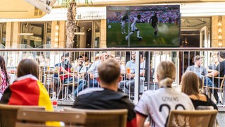 Fans sitzen in einem Restaurant und schauen ein EM-Spiel auf einem Fernseher. (Archivbild)