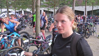 Die Triathletin Lea van Beek beim City-Triathlon, im Hintergrund viele Fahrräder