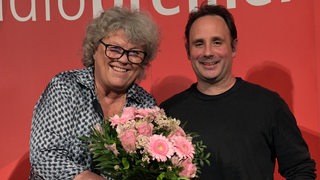Anne Holt (mit Blumenstrauß) und Jan Costin Wagner lächeln in die Kamera