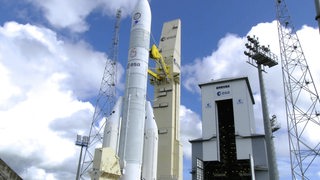Die neue Ariane 6 Rakete steht startbereit an einem Turm.