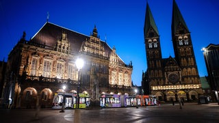 Das Rathaus Bremen, daneben der Dom. Im Vordergrund fährt eine Straßenbahn.