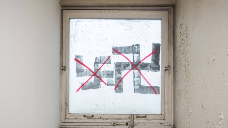 Zwei durchgestrichene Hakenkreuze sind an ein altes Fenster gesprüht worden.