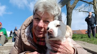 Eine Frau sitzt auf einer Treppe und hält ihren Hund im Arm