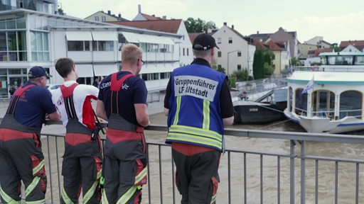 Rettungskräfte schauen von einer Brücke.