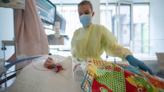 Eine Intensivpflegerin versorgt einen am Respiratorischen Synzytial-Virus erkrankten Patienten, der beatmet wird.