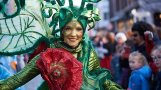 Frau mit grüner Maske und Kostüm beim Samba-Umzug