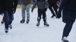 Kinder und Erwachsene laufen Schlittschuh auf einer Eisbahn