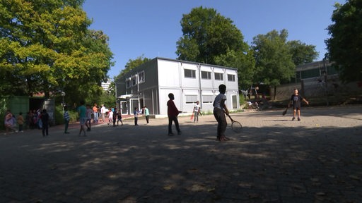 Mehrere Kinder spielen und gehen auf einem kleinen Schulhof