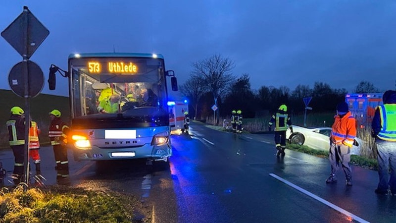 Einsatzkräfte stehen neben einem Bus auf einer Straße.