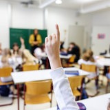 Schülerinnen und Schüler melden sich in einem Klassenraum.