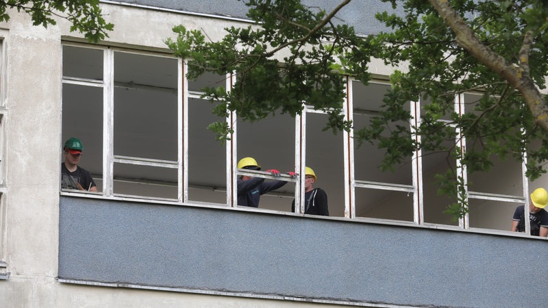 Bauarbeiter entfernen Fensterrahmen in einem Schulgebäude (Archivbild)