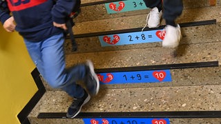 Grundschüler gehen auf einer Flurtreppe in die Pause (Symbolbild)