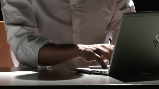 Eine Person tippt auf einem Laptop.