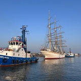 Ein Segelschiff wird von zwei Schlepper geschleppt.