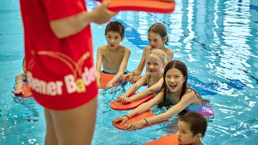Kinder in einem Schwimmbad, im Vordergrund Frau mit Schriftzug "Bremer Bäder"