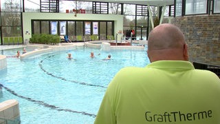 Ein Bademeister schaut in ein Becken in einem Schwimmbad.