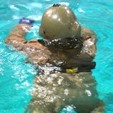 Ein Soldat schwimmt in Uniform und mit Helm im Wasser