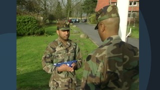 Zwei US amerikanische Soldaten in Unifrom machen sich bereit, eine Flagge zu hissen.