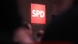 Leuchtenes SPD Logo, davor unscharf Menschen (Symbolbild)