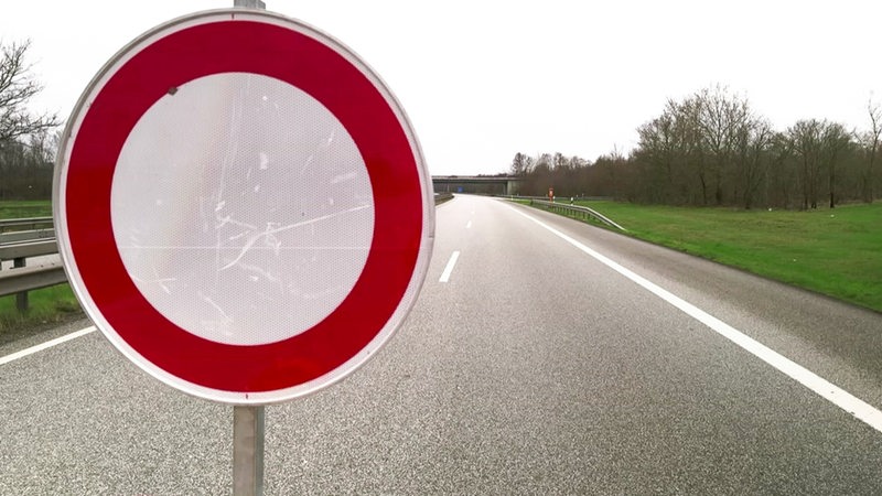 Es ist ein "Durchfahrt verboten"-Verkehrsschild vor einer leeren Autobahn zu sehen.