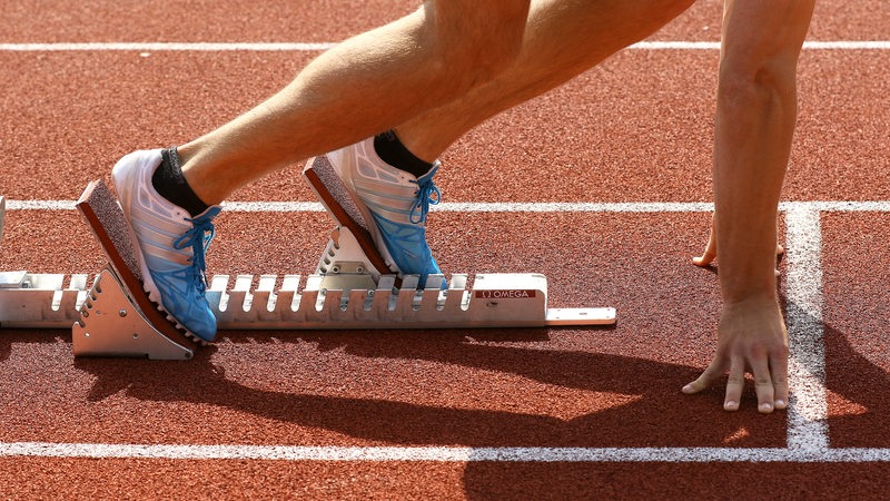 Beine und Schuhe eines Leichtathleten im Startblock