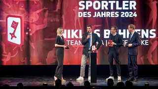 Der Radsportler Niklas Behrens wird auf der Bühne des GOP Varietés aks Bremens Sportler geehrt, neben ihm die Moderatoren Janna Betten und Nils Holst und der Chefredakteur des Weser-Kuriers Benjamin Piel.