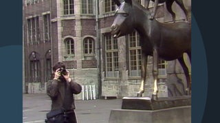 Eine Archivaufnahme eines Touristen der die Bremer Stadtmusikanten fotografiert