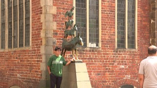 Zu sehen ist ein Junge, der für ein Bild vor den Bremer Stadtmusikanten posiert.