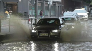 Ein Auto fährt durch eine überschwemmte Strasse in der Bremer Innenstadt.