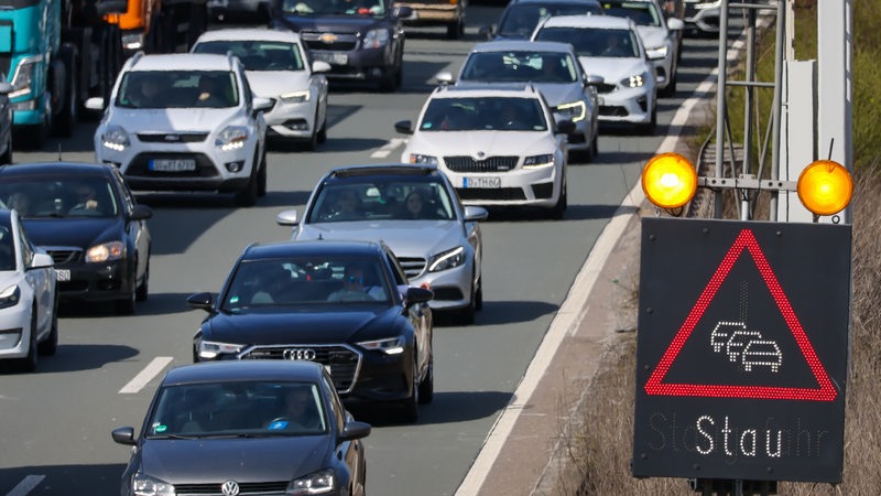 Autos stauen sich auf einer Autobahn, mit Schild "Stau"