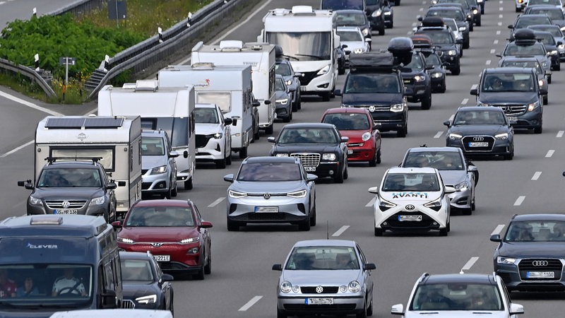 Zahlreiche Autos und Wohnwagen stehen in einem Stau auf einer Autobahn.