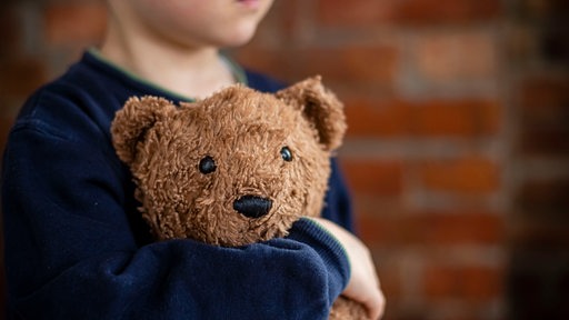 Ein kleiner Junge kuschelt mit seinem Teddybär.