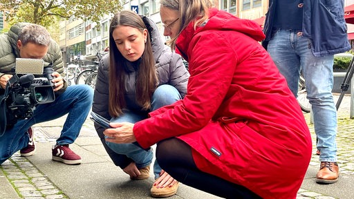 Eine Schülerin zeigt Sascha Aulepp die Funktionsweise der App für die Stolpersteine in Bremen