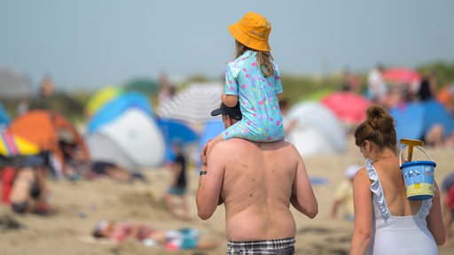 Eine Familie läuft an einem Nordsee-Strand entlang.