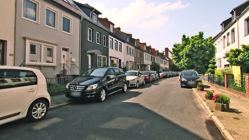 Zu sehen sind auf den Gehwegen parkende Autos in einer Straße.