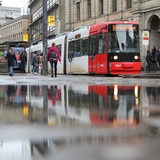 Eine Straßenbahn an der Haltestelle Domsheide in Bremen spiegelt sich in einer Pfütze.