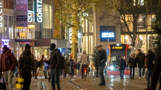 Menschen laufen und eine Straßenbahn fährt durch die dunkle Bremer Innenstadt.